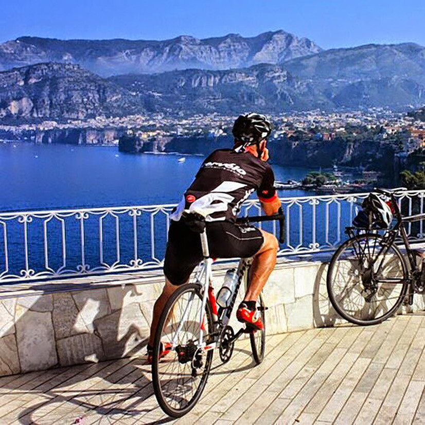 Cyclist pausing to admire the view over a coastal town on the Amalfi Coast