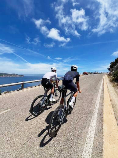 Cyclists riding along a scenic coastal road in Southern Italy