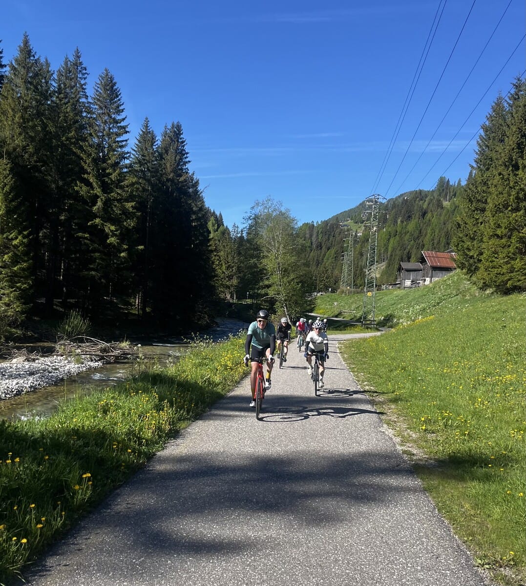 Cyclists riding along a forest bike path in the Dolomites