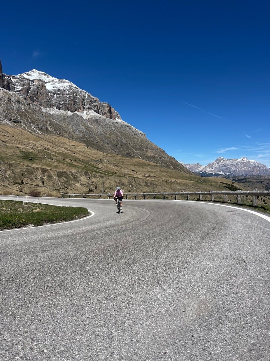 Cyclist riding a mountain road with the Dolomites in view