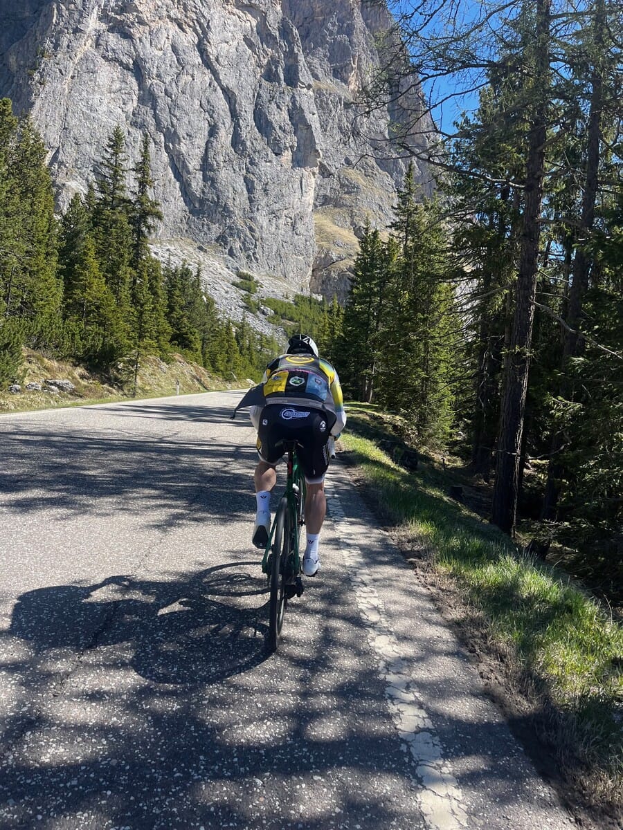 Cyclist riding a forest road beside a rock face in the Dolomites