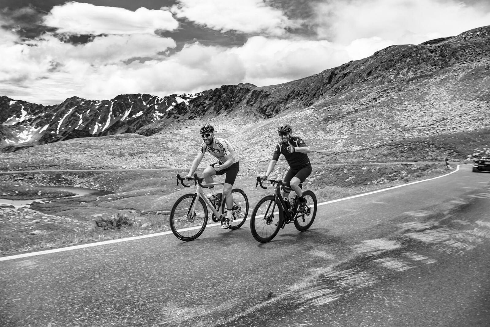 Black and white photo of two cyclists climbing a mountain pass