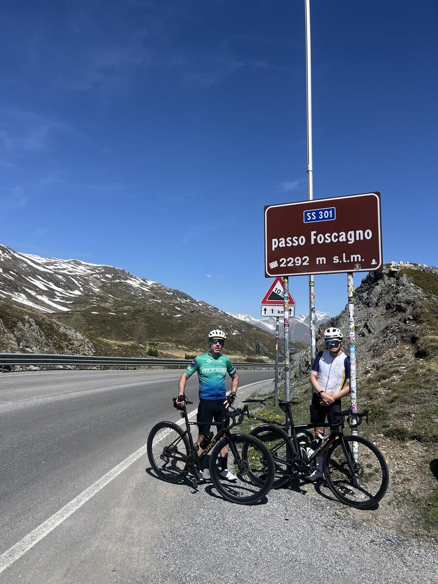Group of cyclists at the Passo di Foscagno sign, 2291m