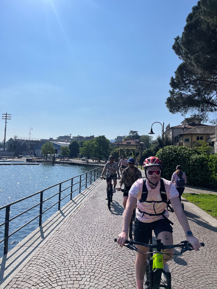 Two cyclists riding e-bikes along the shore of Lake Como